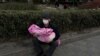 北京一家兒童醫院外一名男子懷抱一個幼童。（2023年11月27日）
