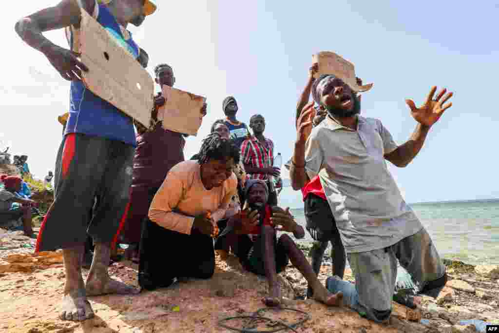 Migrants from Africa react after being stranded on the seashore at the Libyan-Tunisian border in Ras Jedir.
