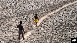 Čovek i dečak prelaze suvo dno reke Jamuna u Nju Delhiju, Indija, 2. maj 2022. (Foto: AP/Manish Swarup)