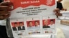 Seorang pekerja memegang surat suara untuk pemilihan presiden 14 Februari yang menunjukkan foto ketiga paslon, saat persiapan distribusi logistik pemilu di Tangerang, Indonesia, 10 Januari 2024. (Foto: Tatan Syuflana/AP Photo)