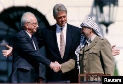 Jicak Rabin, premijer Izraela se rukuje sa Jaserom Arafatom, liderom PLO-a, uz prisustvo Bila Klintona, američkog predsednika posle potpisivanja sporazuma iz Osla (Foto: Reyters/Gary Hershorn)