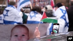 Seseorang mengibarkan bendera Palestina di luar Mahkamah Internasional di Den Haag, Belanda, 12 Januari 2024. (Foto: AP)
