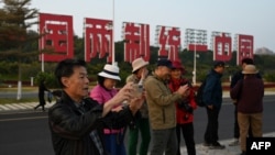 中國福建廈門豎立起一個台灣金門島可以看到的「一國兩制統一中國」的大型標語牌，旅遊者在前拍照。（2024年1月12日）