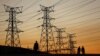 FILE - Locals walk past electricity pylons in Soweto, South Africa, July 3, 2022. Matshela Koko, the former head of the country's power provider Eskom has been charged with multiple counts related to corruption, fraud and money laundering.