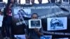 FILE - East Timorese journalist Raimundos Oki holds a placard during a rally to support him, in Dili, May 29, 2017. Charges of defamation against Oki were dropped in that case, but he now is under investigation in a new case, accused of having breached judicial secrecy.