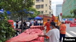 中國廣東深圳的工人正在準備給一住宅小區外豎立圍欄，與此同時小區居民正在排隊做核酸。 （2022年8月29日）