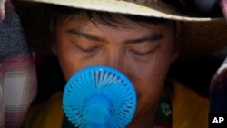 Volonter koristi mali ventilator da se rashladi dok čeka dolazak pape Franje nedaleko od Lisabona (Foto: AP Photo/Armando Franca)