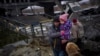 Local militiaman Valery, 37, carries a child as he helps a fleeing family across a destroyed bridge, on the outskirts of Kyiv, Ukraine, March 2. 2022. 
