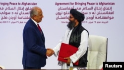 Mula Abdul Gani Baradar, lider delegacije talibana, i Zalmaj Kalilzad, izaslanik SAD za mir u Avganistanu, ruku ju se nakon potpisivanja sporazim u Dohi, Katar.