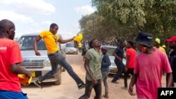 A man, suspected of being a ruling ZANU-PF attacker, reacts after being kicked by a supporter of the opposition Citizens Coalition for Change during an electoral rally, Feb. 27, 2022, at Mbizo shopping center in Kwekwe.