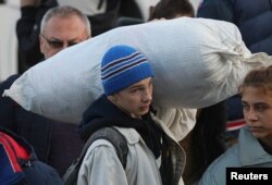 Arhiva - Dečak nosi vreću dok civili evakuisani iz oblasti Herson u Ukrajini, pod kontrolom Rusije, stižu na lokalnu železničku stanicu, nakon što su ruski zvaničnici proširili naredbu za evakuaciju na područje duž istočne obale reke Dnjepar, u gradu Džankoj, Krim, 2. novembar 2022.