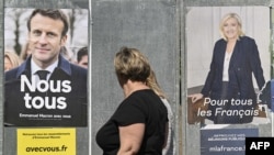 Žena hoda ispred predizbornih plakata Emanuela Makrona i Marin le Pen, pred predsedničke izbore u Franuskoj.