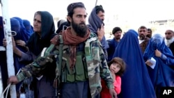 Talibanski borac na straži dok ljudi primaju obroke hrane koje deli saudijska humanitarna grupa, Kabul, Avganistan, 25. april 2022.(Foto: AP/Ebrahim Noroozi)