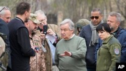 Generalni sekretar UN Antonio Gutereš razgovara sa lokalnim sveštenikom stojeći blizu masovne grobnice u Buči, u predgrađu Kijeva, 28. aprila 2022. 