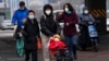 A child wearing a mask is pushed across a road in Beijing, Dec. 2, 2022. 