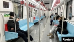 FILE - Commuters wear protective masks while they ride a subway in Shanghai, China, Dec. 20, 2022.