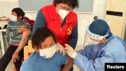 FILE - A medical worker administers a dose of a vaccine against COVID-19 to an elderly resident, during a government-organized visit to a vaccination center in Zhongmin village on the outskirts of Shanghai, Dec. 21, 2022.