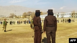 FILE - Personel keamanan Taliban berjaga menjelang hukuman cambuk di depan umum terhadap perempuan dan laki-laki di sebuah stadion sepak bola di kota Charikar, provinsi Parwan, pada 8 Desember 2022. (AFP)