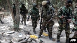 FILE - Members of the Senegalese Armed Forces walk past discarded rockets at a recently captured Movement of Democratic Forces of Casamance (MFDC) rebel base in Blaze Forest, Feb. 9, 2021. 