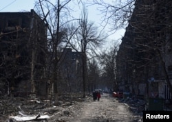 Local residents walk past residential buildings which were damaged during Ukraine-Russia conflict in the besieged southern port city of Mariupol, Ukraine, March 18, 2022.
