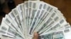 FILE - A woman shows Myanmar banknotes in Yangon, Myanmar, June 9, 2011. 