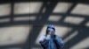 A worker in protective suit wipes his face shield at a coronavirus testing side in Beijing, Monday, Dec. 5, 2022. 