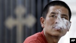 一名男子在北京一家教堂外吸煙(資料圖片)