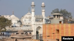 Seorang pekerja berdiri di atap kuil yang bersebelahan dengan Masjid Gyanvapi menjelang peresmian koridor baru Kuil Kashi Vishwanath oleh Perdana Menteri India Narendra Modi di kota utara Varanasi, India, 12 Desember 2021. (Foto: REUTERS/Pawan Kumar )