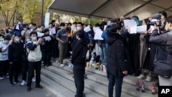北京清華大學的學生手舉白紙抗議嚴厲的防疫政策，悼念日前在新疆烏魯木齊市死於火災的至少10名遇難者。 （2022年11月27日）