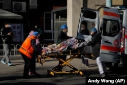 A patient is wheeled into the fever clinic at a hospital in Beijing, Monday, Dec. 19, 2022. Chinese health authorities on Monday announced two additional COVID-19 deaths, both in the capital Beijing, that were the first reported in weeks and come during an expected surge of illnesses after the nation eased its strict "zero-COVID" approach. (AP Photo/Andy Wong)