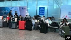 Putnici čekaju da se ukrcaju u autobuse i odu u karantinske hotele i objekte sa aerodroma Guangžou Bajun u južnoj Kini. 25. decembar 2022. (Foto: AP/Emily Wang Fujiyama)