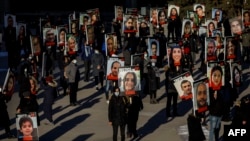FILE - People hold signs with images of the victims of the downed Ukraine International Airlines flight PS752, in Toronto, Canada, Jan. 8, 2021.