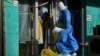 Workers in protective gear prepare to collect COVID samples from a woman at her locked down store in Beijing, Dec. 1, 2022. 