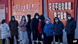 北京市民在宣傳習近平思想的標語牆前排隊等候接受核酸檢測。 （2022年12月5日）