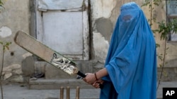 Seorang perempuan Afghanistan berpose untuk foto sambil memegang tongkat kriketnya di Kabul, Afghanistan, pada Jumat, 11 November 2022. (Foto: AP)