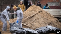 Ljudi u zaštitnoj odeći ekshumiraju tela civila ubijenih tokom ruske okupacije Buče, gradića na obodu Kijeva, 13. aprila 2022.