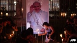 People place lit candles close to a picture of Pope Francis during a vigil to pray for his health in Buenos Aires on March 7, 2025.