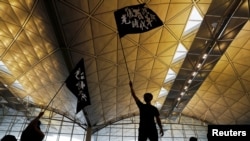 (资料照) 2019年8月12日，香港反“送中”抗议者参加抗议集会。示威者的旗帜上写的是“光复香港，时代革命”。
