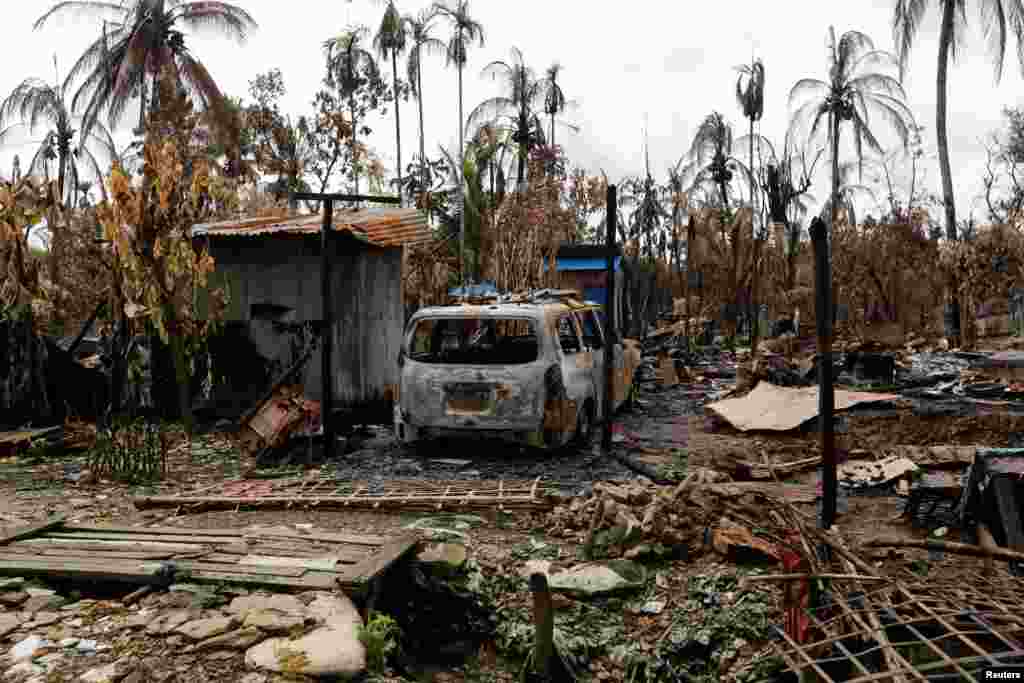 A car is seen near a house that was burnt down during the last several days of violence in Maungdaw, Myanmar.