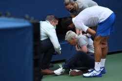 Novak Đoković (desno) stoji pored linijske sudije koju je nenamerno pogodio lopticom u grlo, 6. septembra 2020. (Credit: Danielle Parhizkaran-USA TODAY Sports)