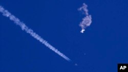 Na fotografiji Čad Fiša, vide se ostaci velikog balona kako padaju ka Atlantskom okeanu, nedaleko od obale Južne Karoline, dok borbeni avion prolazi pored ostavljajući kondenzacijski trag, 4. februara 2023.