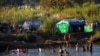 FILE - Refugees, who have fled fighting in Myanmar, bathe in the river on the Thai-Myanmar border, in Mae Sot, Thailand, Jan. 7, 2022. 