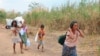 Para warga Myanmar yang kehilangan tempat tinggal akibat situasi yang tak menentu di negaranya, berjalan membawa bantuan makan siang yang mereka dapat ke tenda tempat mereka tinggal di tepian sungai Moei di Mae Sot, Thailand, pada 5 Februari 2022. (Foto: AP)