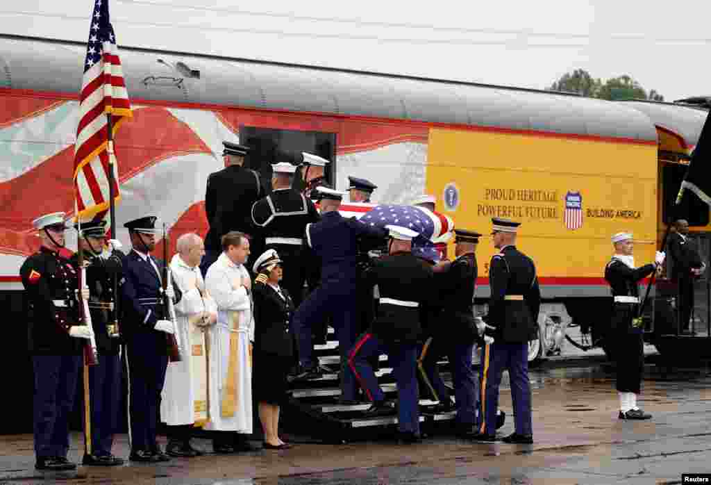 The flag-draped casket of the U.S.'s 41st President George H.W. Bush is carried by a joint services military honor guard in Spring, Texas, as it is placed on a Union Pacific train. The train will take about 2 hours to travel roughly 143 kilometers to the city of College Station, home to Bush's presidential library at Texas A&M University. The locomotive has been painted the colors of the Air Force One plane used during his presidency and bears the number "4141" in honor of the 41st president.