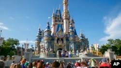 FILE - Performers dressed as Mickey Mouse, Minnie Mouse, Goofy, Donald Duck and Daisy Duck entertain visitors at Cinderella Castle at Walt Disney World Resort in Lake Buena Vista, Florida, on April 18, 2022.