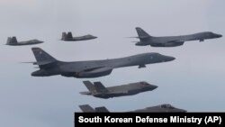 In this photo provided by South Korean Defense Ministry, U.S. Air Force B-1B bombers, center, F-22 fighter jets and South Korean Air Force F-35 fighter jets, bottom, fly during a joint air drill in South Korea, Jan. 1, 2023. 