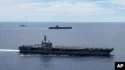 FILE - In a photo provided by the U.S. Navy, U.S. warships sail together in formation, in the South China Sea, July 6, 2020.