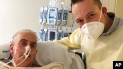FILE - David Bennett Jr., right, stands next to his father's hospital bed in Baltimore, Md., Jan. 12, 2022, in this photo provided by the University of Maryland School of Medicine.