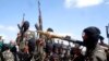 FILE - Armed al-Shabab fighters ride on pickup trucks as they prepare to travel into Mogadishu, Somalia, Dec. 8, 2008. 