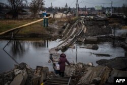 A woman crosses a destroyed bridge in Bakhmut, Donetsk region, Jan. 6, 2023, amid the Russian invasion of Ukraine.